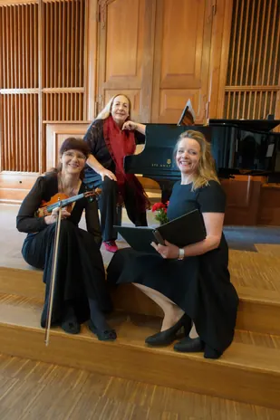 The trio on the stage steps in front of the Steinway grand piano