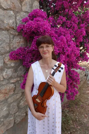 Katalin Kertész with her violin in front of flowering bougainvillea